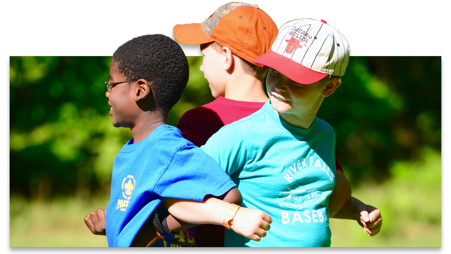 Three young boys have their arms locked as they complete a team-building game